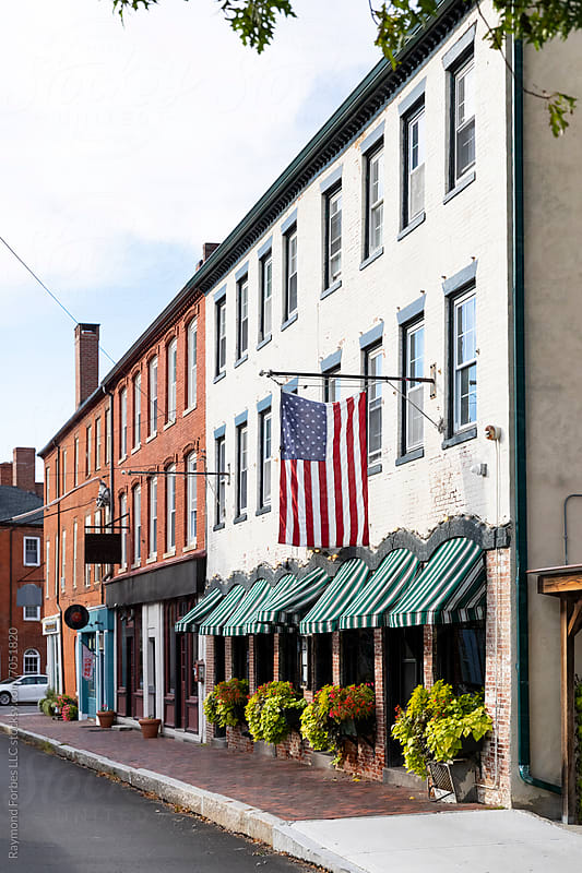 American flag over a downtown sidewalk of independent shops